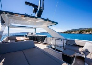 Luxurious 2022 Pearl 62 yacht deck with seating, ocean view, and clear blue sky.