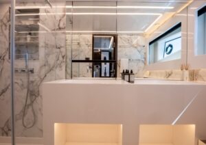 Luxurious modern bathroom with marble walls, sleek fixtures, and ambient lighting on a 2022 Pearl 62 yacht.