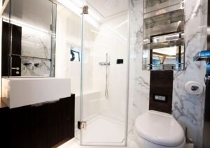 Luxurious modern bathroom with marble walls, glass shower, and sleek fixtures in a 2022 Pearl 62 model.