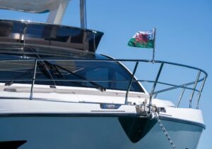 2022 Pearl 62 yacht with Welsh flag, sleek design, anchored under clear blue sky.