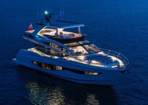 Luxurious 2023 Pearl 62 yacht illuminated on calm evening waters.