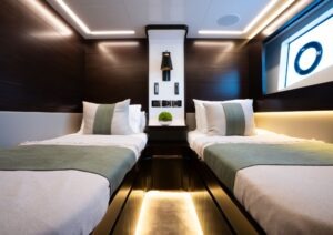 Luxurious 2023 Pearl 62 yacht cabin with twin beds and modern lighting.