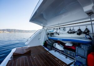 2023 Pearl 62 yacht with open storage compartment, paddleboard, and scenic ocean view.