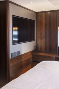 Luxurious interior of 2021 Sunseeker Manhattan 68 yacht with sleek wood paneling and modern TV.