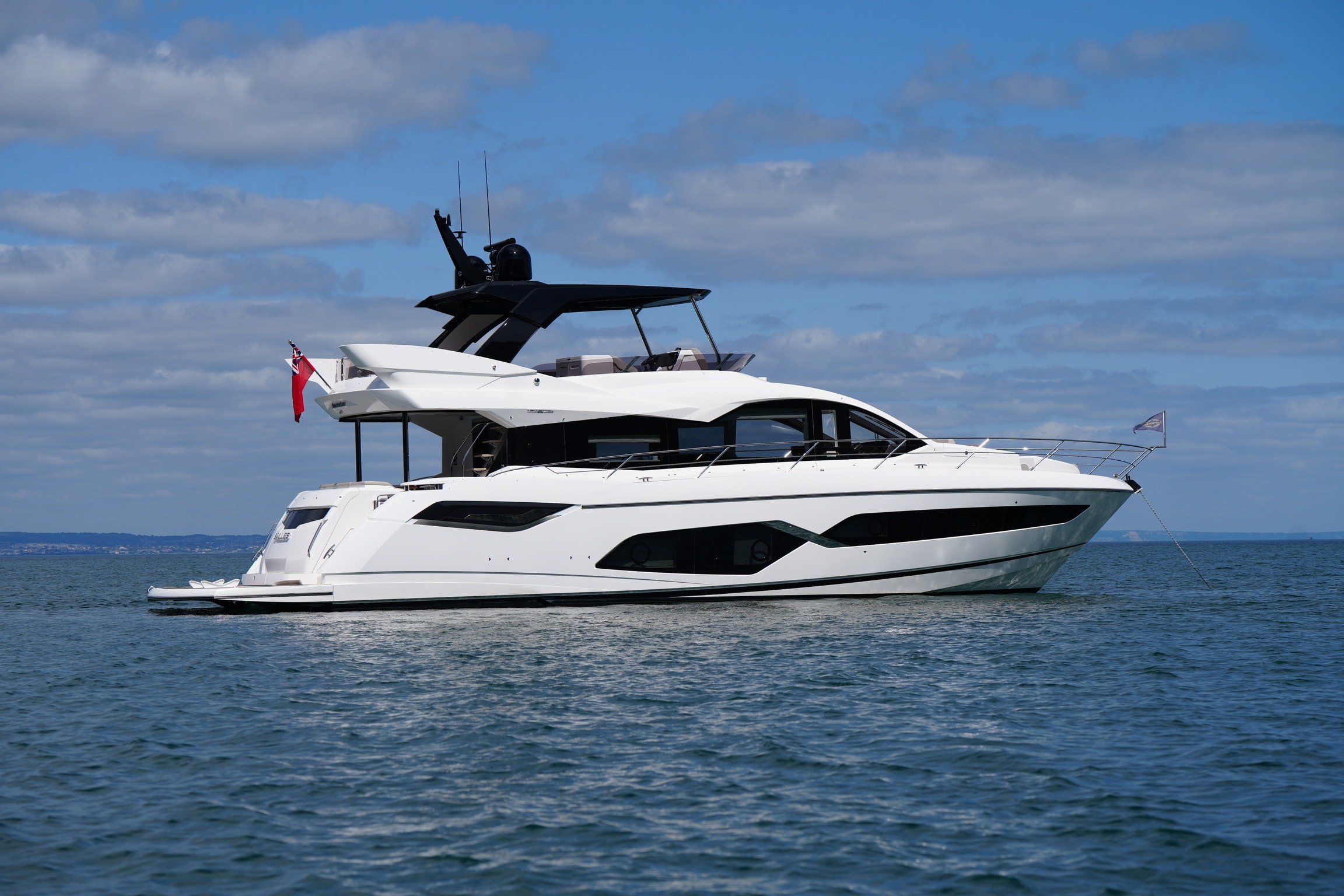 Luxury 2021 Sunseeker Manhattan 68 yacht on calm ocean waters under blue sky.