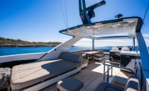 Luxurious 2022 Pearl 62 yacht deck with seating, ocean view, and clear blue sky.