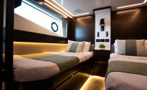 Luxurious 2023 Pearl 62 yacht cabin with twin beds, modern lighting, and elegant decor.