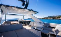 Luxurious 2022 Pearl 62 yacht deck with seating, ocean view, and clear blue sky.