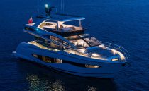 Luxurious 2023 Pearl 62 yacht illuminated on calm evening waters.