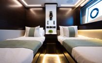 Luxurious 2023 Pearl 62 yacht cabin with twin beds and modern lighting.
