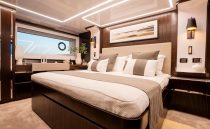 Luxurious 2023 Pearl 62 yacht bedroom with modern decor and ambient lighting.