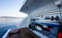 2023 Pearl 62 yacht with open storage compartment, paddleboard, and scenic ocean view.