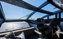 Luxurious interior of 2022 Pearl 62 yacht with panoramic windows and modern helm.