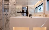 Luxurious modern bathroom with marble walls, sleek fixtures, and ambient lighting on a 2022 Pearl 62 yacht.