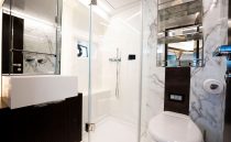 Luxurious modern bathroom with marble walls, glass shower, and sleek fixtures in a 2022 Pearl 62 model.