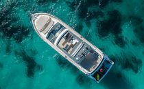 Aerial view of 2022 Pearl 62 yacht on clear turquoise water.