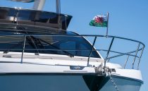 2022 Pearl 62 yacht with Welsh flag, sleek design, anchored under clear blue sky.